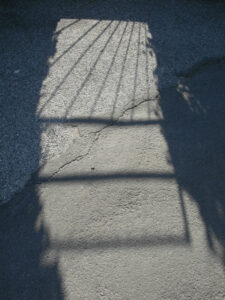 Gartentorschatten auf rissigem Asphalt